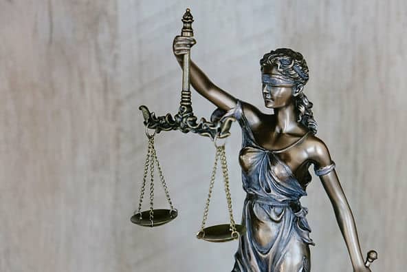 Bronze statue of Lady Justice wearing a blindfold, holding scales in her left hand and a raised sword in the right.